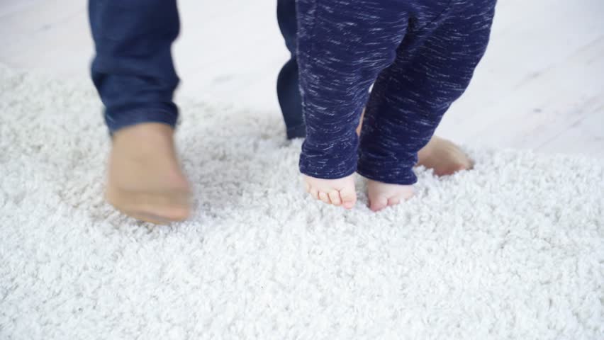 Mother halping her 6 months to make first steps