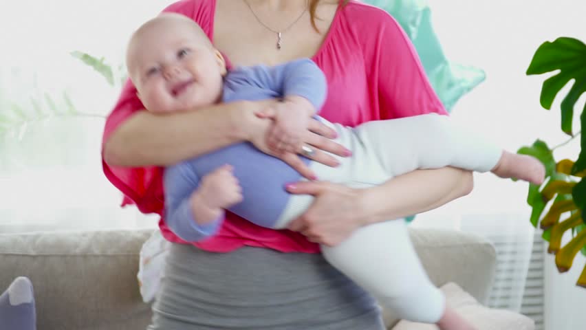 Pretty mother playing with her 6 months son in room closeup slow motion