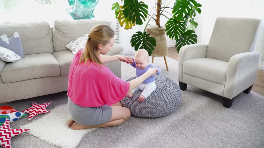Young mother playing with her 6 months son in room