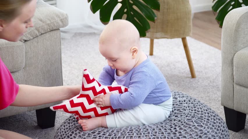 Young mother playing with her 6 months son in room closeup