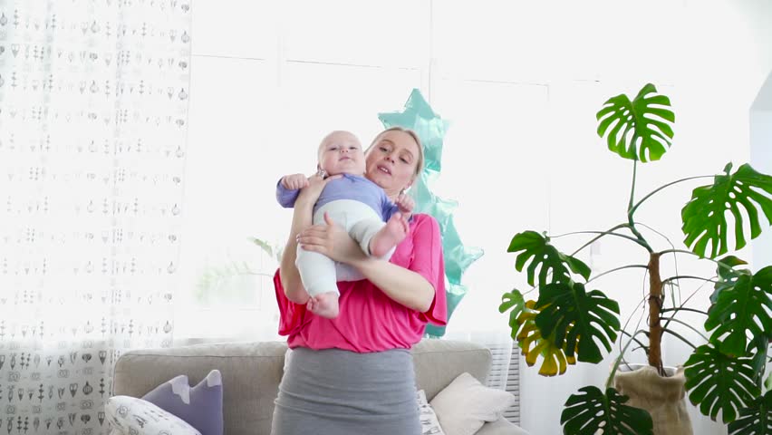 Pretty mother playing with her 6 months son in room