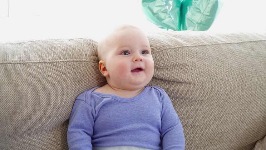 Pretty cute little child boy of 6 monts sitting on sofa closeup