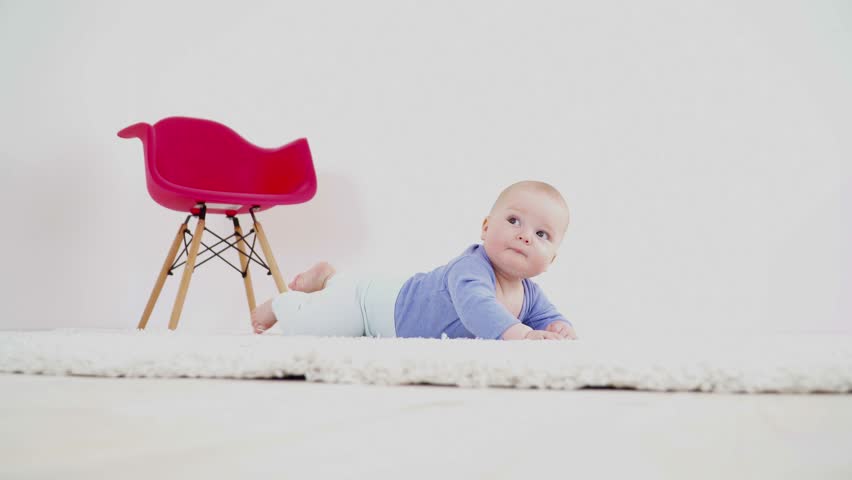 Pretty cute baby boy of 6 months laying on carpet