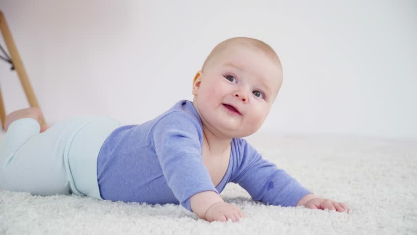Pretty little baby boy of 6 months laying on carpet closeup