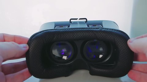 Man Takes Off Virtual Reality Glasses. it Becomes Visible Large Round Lenses in Which Something Shows. in the Room is Light and in Glasses Barely Visible Blue Picture.