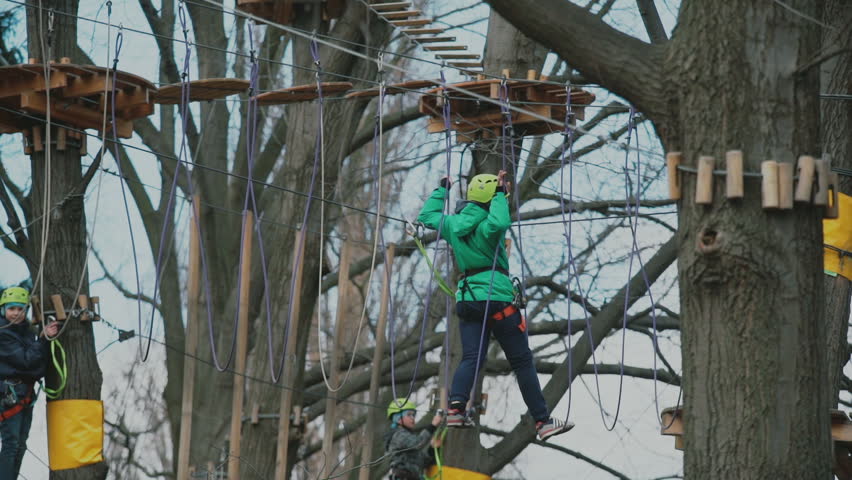 young boy passing the cable route high among trees, extreme sport in adventure park