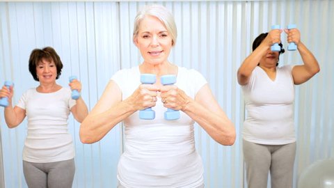 Elderly female gym members using weights yoga fitness class