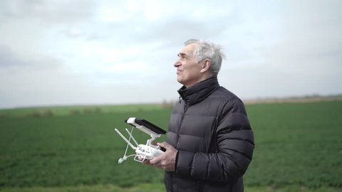 Senior man is getting experience controlling drone at nature. 4K.