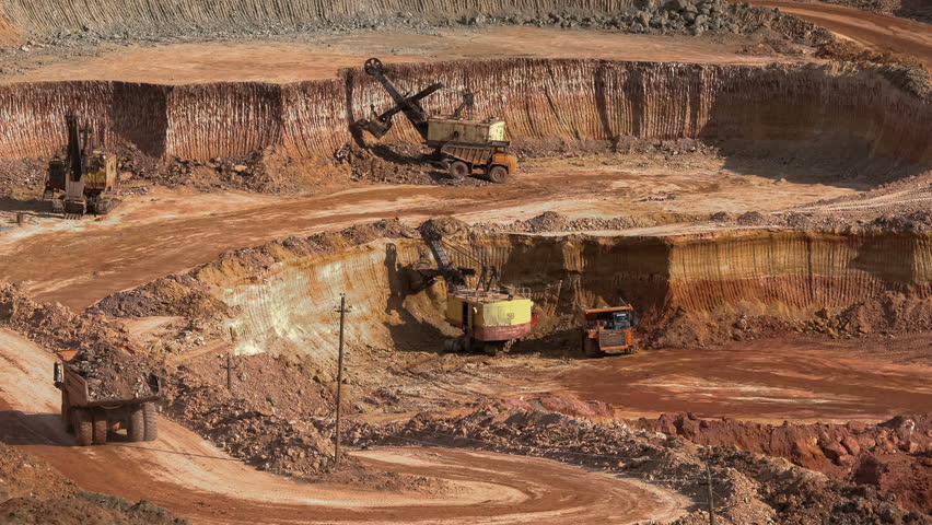 Excavators load ore into dump-trucks. This area has been mined for buaxite, aluminum and other minerals. Open-cast. Operating mine. Bauxite quarry. Royalty-Free Stock Footage #26337341