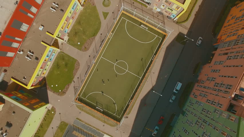 Above top view children play football soccer at school stadium aerial 4K UHD