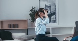 Excited Caucasian female in casual clothes using VR headset indoors, watching scary horror 360 video. 4K UHD RAW edited footage