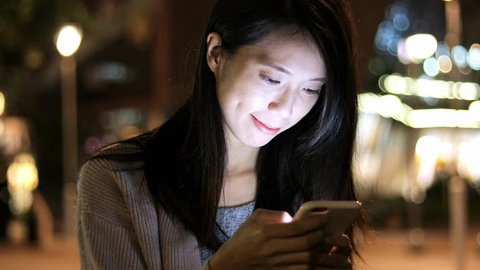 Woman watching on cellphone at night 