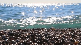 Beautiful blue sea water background with bright sunny sparkles on surface of waves. Defocused people swimming in sea. Real time full hd video footage.