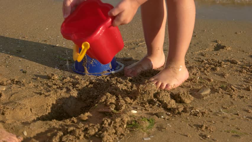 Children playing on the seashore. Leg of kid stomping mud. Starting all over.