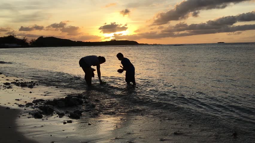 Guam, Japan - March 20, 2017: Child with his mom silhouette at beach in Guam