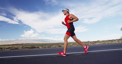 Triathlon - Triathlete man running in triathlon suit training for ironman race. Male runner exercising on Big Island Hawaii.
