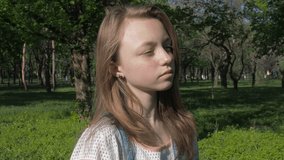 The face of a teenage girl with freckles. Beautiful girl face close-up. A girl on a sunny day outdoors adjusts her hair.