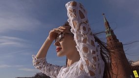 Young beautiful woman in white dress standing on the deck of boat passing Moscow Kremlin. 4K video