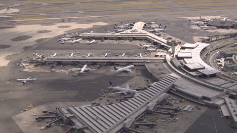 AERIAL, CLOSE UP: Flying above airplanes parked on apron waiting for passengers to board through jetway and start their traveling journey. Terminal building on New York Newark international airport