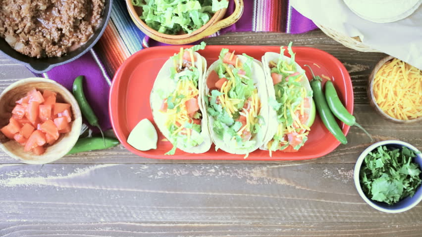 Ground beef tacos with romaine lettuce, diced tomatoes, and shredded cheddar cheese.