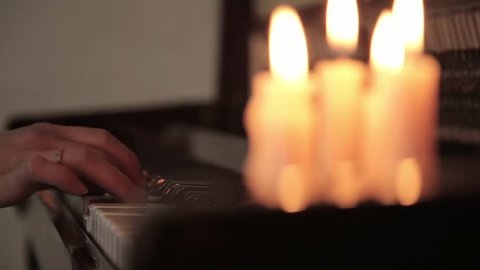 Play piano. female hands playing the piano of candle light. Fingers on the piano.