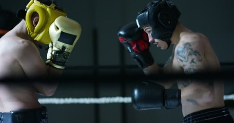 Professional sparring of two (young) partners of boxers in the ring, practice strike technique, rack, defense and endurance, in protective helmets. Concept: love sports, young boxers, love to win.
