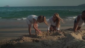 Happy mother and daughters build a sand castle on the beach of the South China Sea, Yalong Bay stock footage video