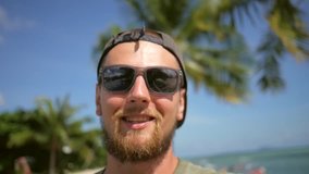 Young Bearded Hipster Man Video Chats on Smart Phone at the Beach. Talking on a Mobile and Doing Selfie. HD Slowmotion. Koh Phangan, Thailand.
