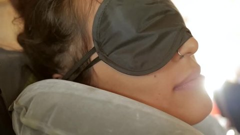 Sleeping Asian Woman Wearing Blindfold Sleeping Mask in Airplane. Young Traveller Girl in the Morning in Plane. HD Slowmotion Lensflare.