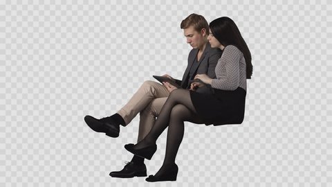 Young man & attractive brunette girl are sitting together and reading PC tablet. Footage with alpha channel