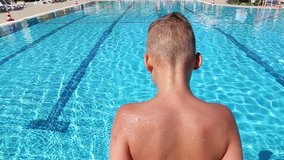 Closeup of back of little child diving and swimming into pool. Real time full hd video footage.