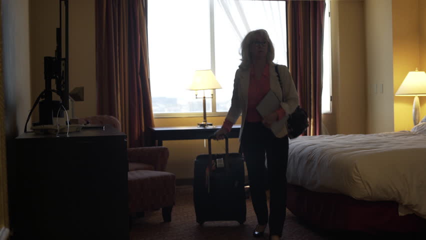 A mature female business traveler packs up her surface tablet and heads out...
