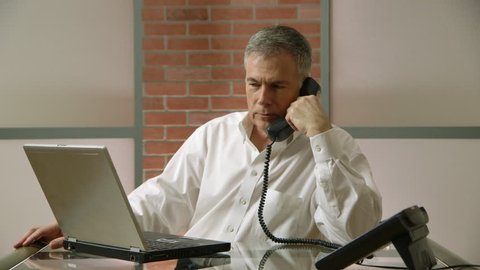 businessman takes a phone call while working at his desk