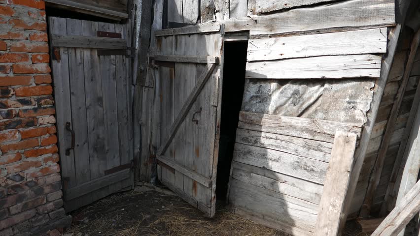 Old doors to the barn. Faded wooden boards. Near the brick wall.
