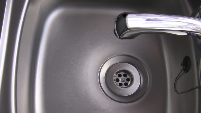 Water from the tap starts dripping slowly into the stainless steel kitchen sink