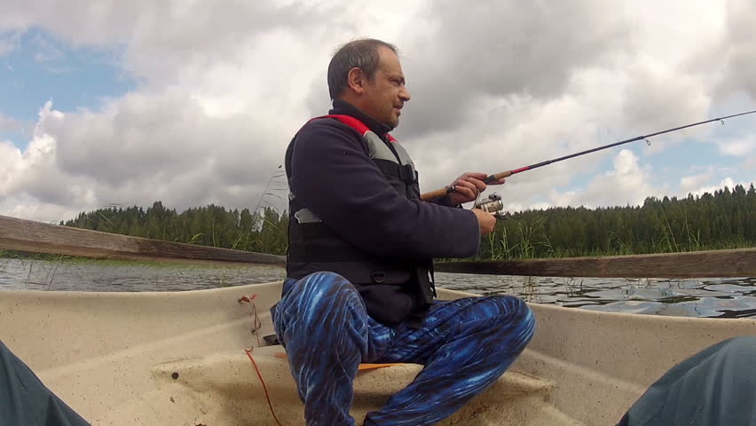 Fisherman catches a fish on spinning with a rowing boat