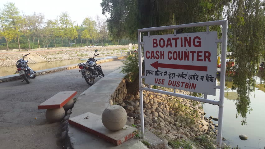 Boating cash counter, use dustbin sign, motorbikes, lake pedal boat ride, India