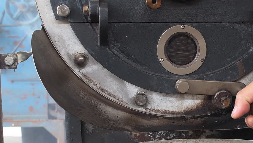 Coffee beans in a large coffee roaster being poured into the cooling cylinder