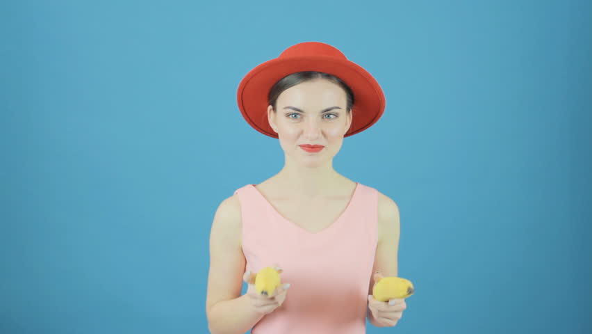 Brunette Girl with Red Hat and Two Bananas is Having Fun on Blue Background in Studio.