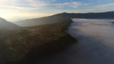 Aerial view flight over Cemoro Lawang, small village in morning mist. Which situated on the edge of massive north-east of Mount Bromo, East Java, Indonesia. 