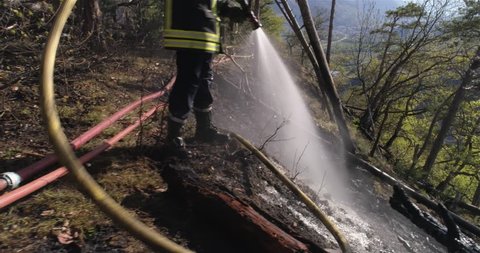 Fireman spraying water, forest burn from april 2017, Lens, Valais - Switzerland - 4K