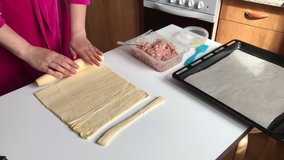Stages of preparation of meat glomeruli. A woman rolls out the dough. Next to the table is a stuffing and lie tools. Video shot on the iPhone 7 Plus.