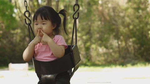 Beautiful Baby East Asian baby girl plays on Swing