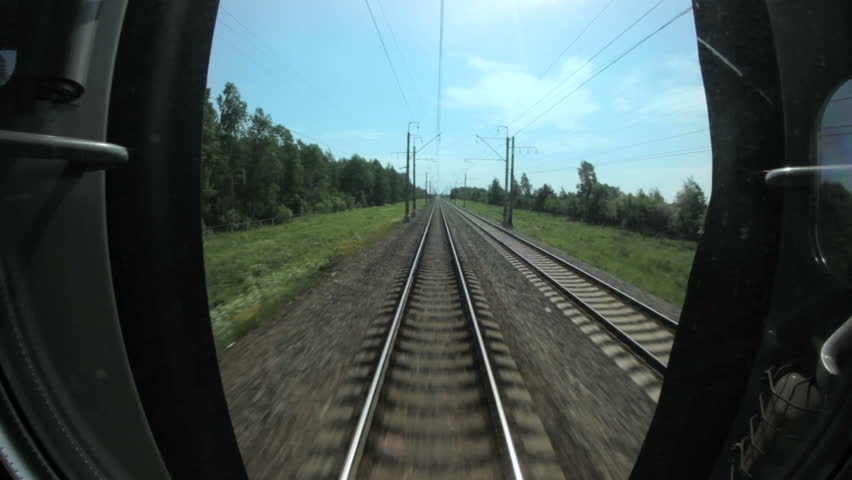 Train travels along rails between trees, railway communications