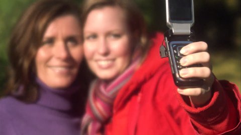 Mother and daughter taking a picture using a mobile phone