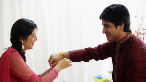 Tilt up shot of a teenage girl tying rakhi to her brothers wrist at Raksha Bhandan festival