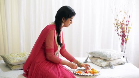Locked-on shot of a teenage girl preparing a puja thali