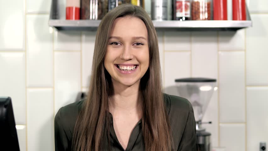 Cheerful waitress standing behind the bar at cafe, beautiful woman in coffee shop near cashbox keeper | Shutterstock HD Video #26470016