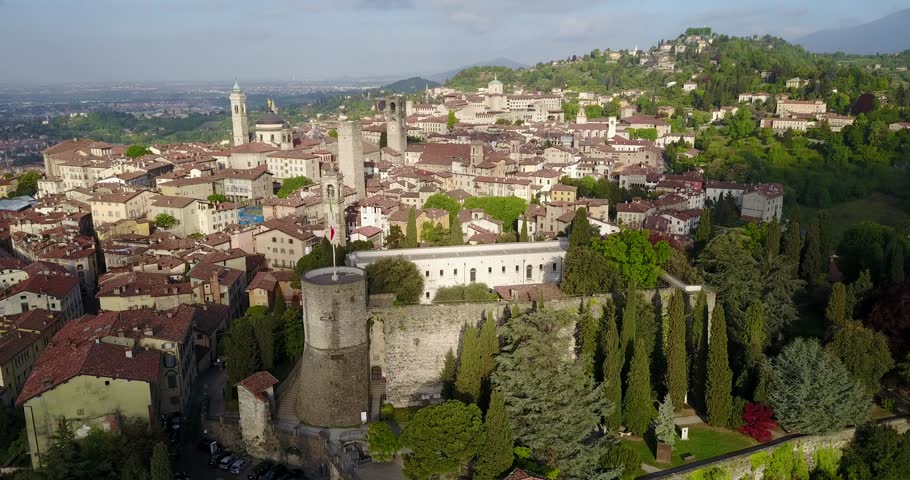 Drone aerial view of Bergamo - Old city (Città Alta), Italy. Landscape on the city center, the main square, the old fortress and its historical buildings during a wonderful blu day