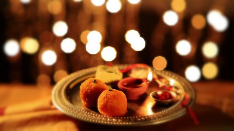 Locked-on shot of a spinning puja thali with rakhi, sweets and oil lamp